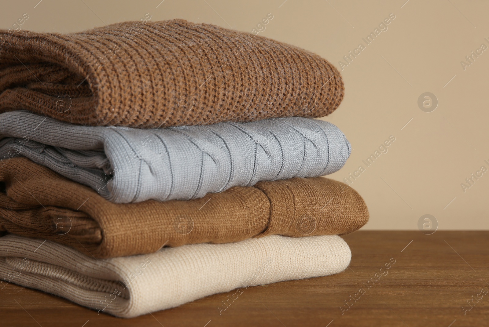 Photo of Stack of folded knitted sweaters on wooden table