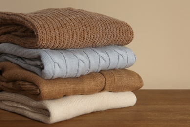 Photo of Stack of folded knitted sweaters on wooden table