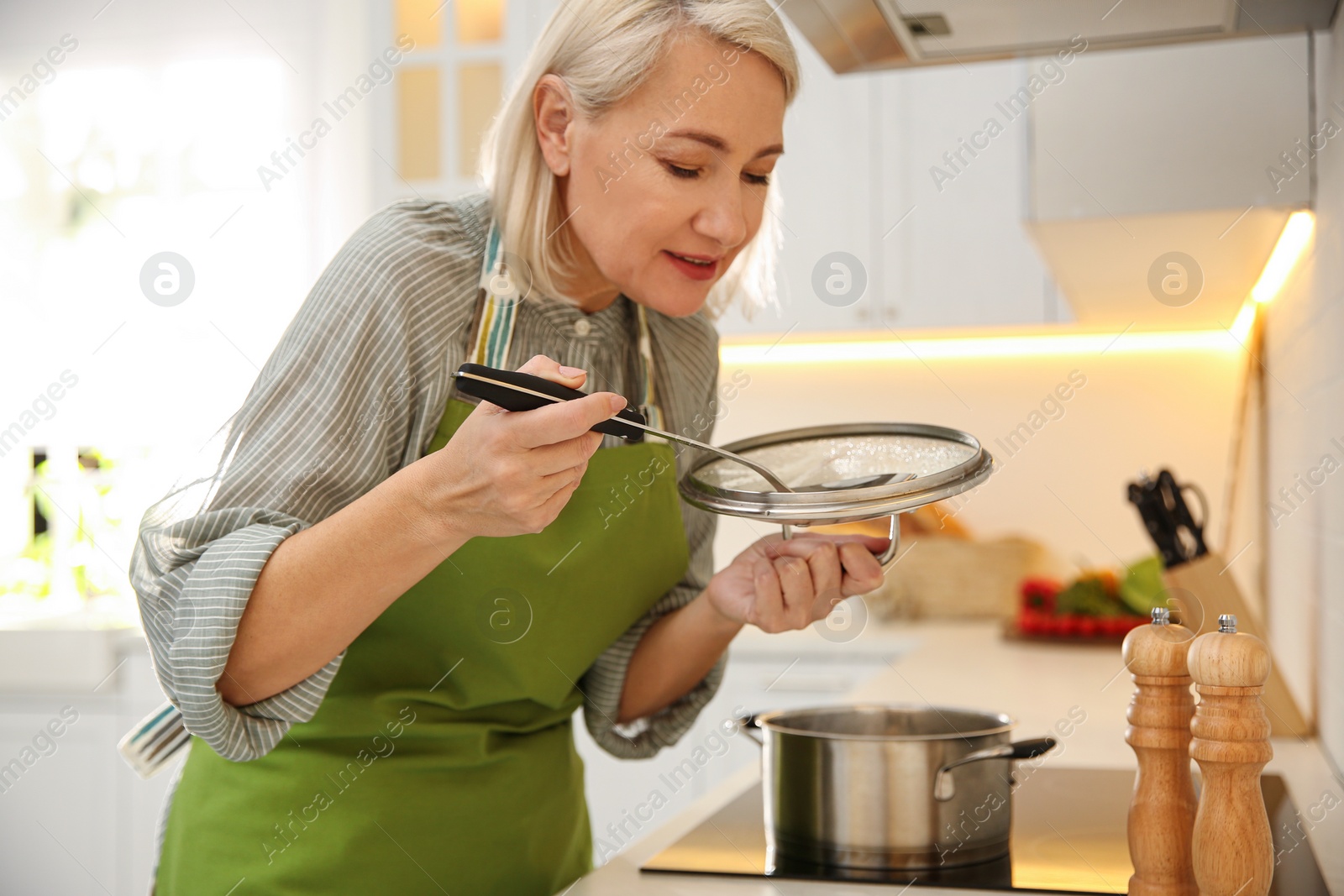 Photo of Mature woman cooking on stove in kitchen