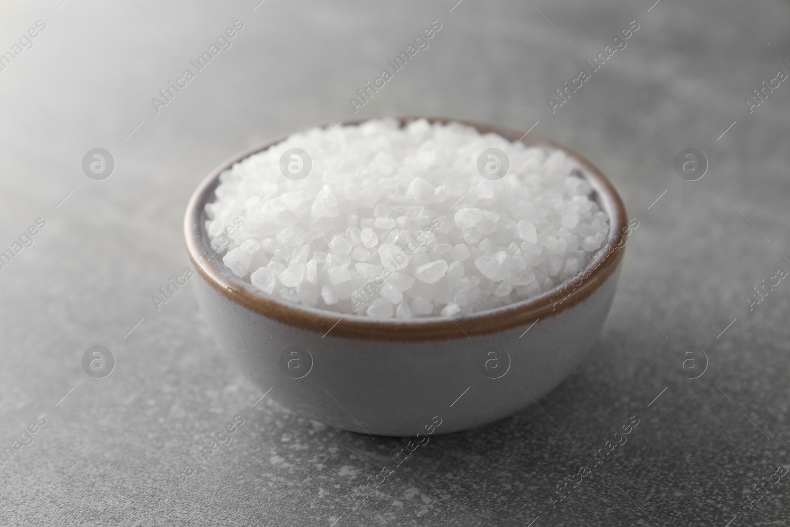 Photo of Bowl of natural sea salt on grey table