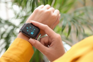 Woman setting smart home control system via smartwatch indoors, closeup. App interface with icons on display