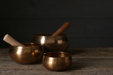 Photo of Golden singing bowls with mallets on wooden table, space for text