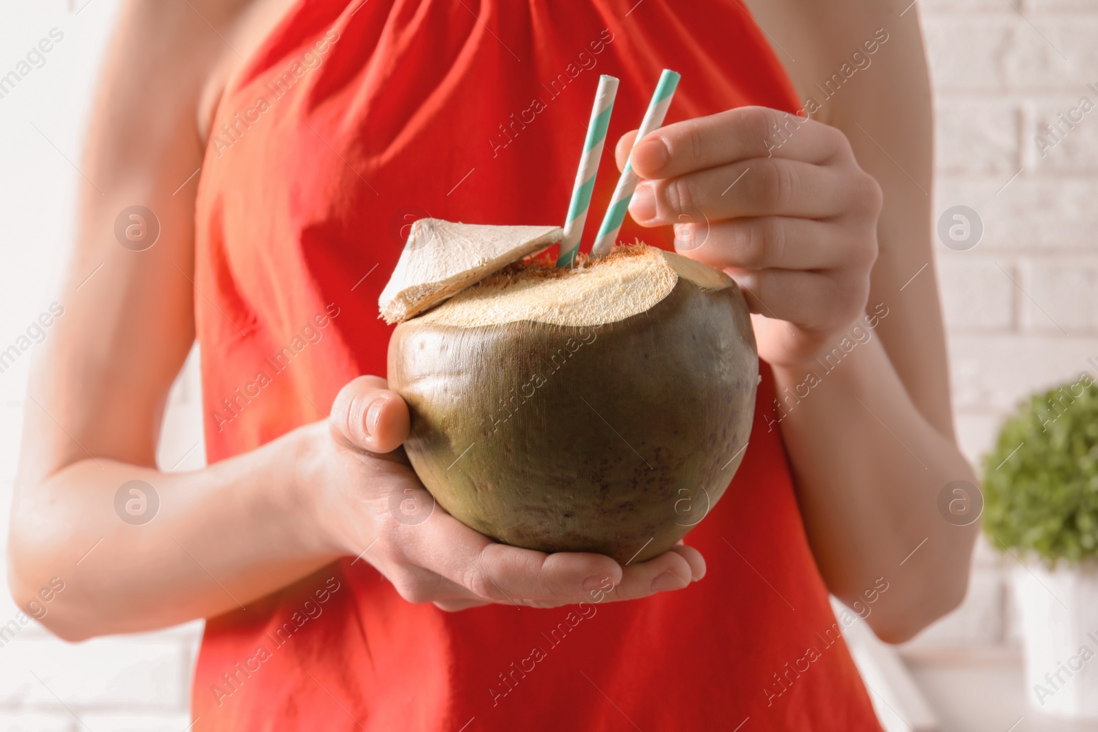 Photo of Young woman with fresh coconut cocktail on blurred background, closeup