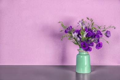 Photo of Vase with beautiful flowers on table against color background. Space for text