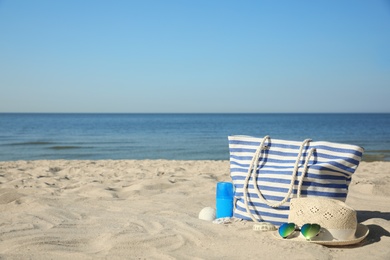 Photo of Stylish beach accessories on sandy sea shore