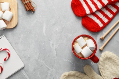 Flat lay composition with cup of tasty cocoa on grey marble table, space for text. Cozy winter