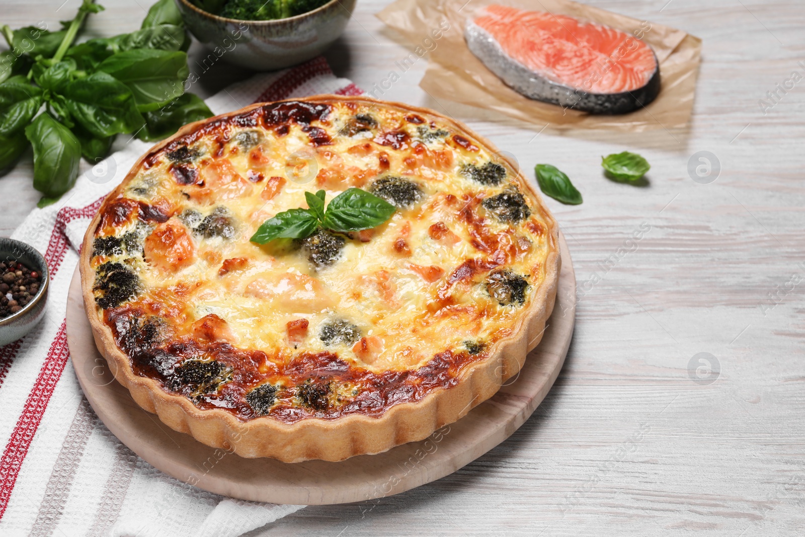Photo of Delicious homemade quiche and ingredients on wooden table