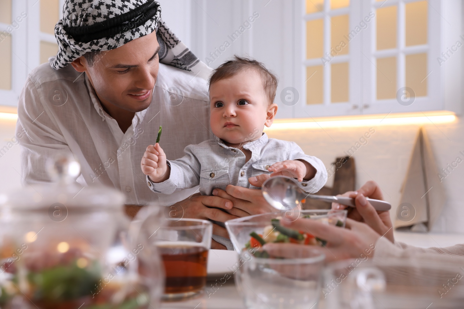 Photo of Happy Muslim family with little son at served table in kitchen