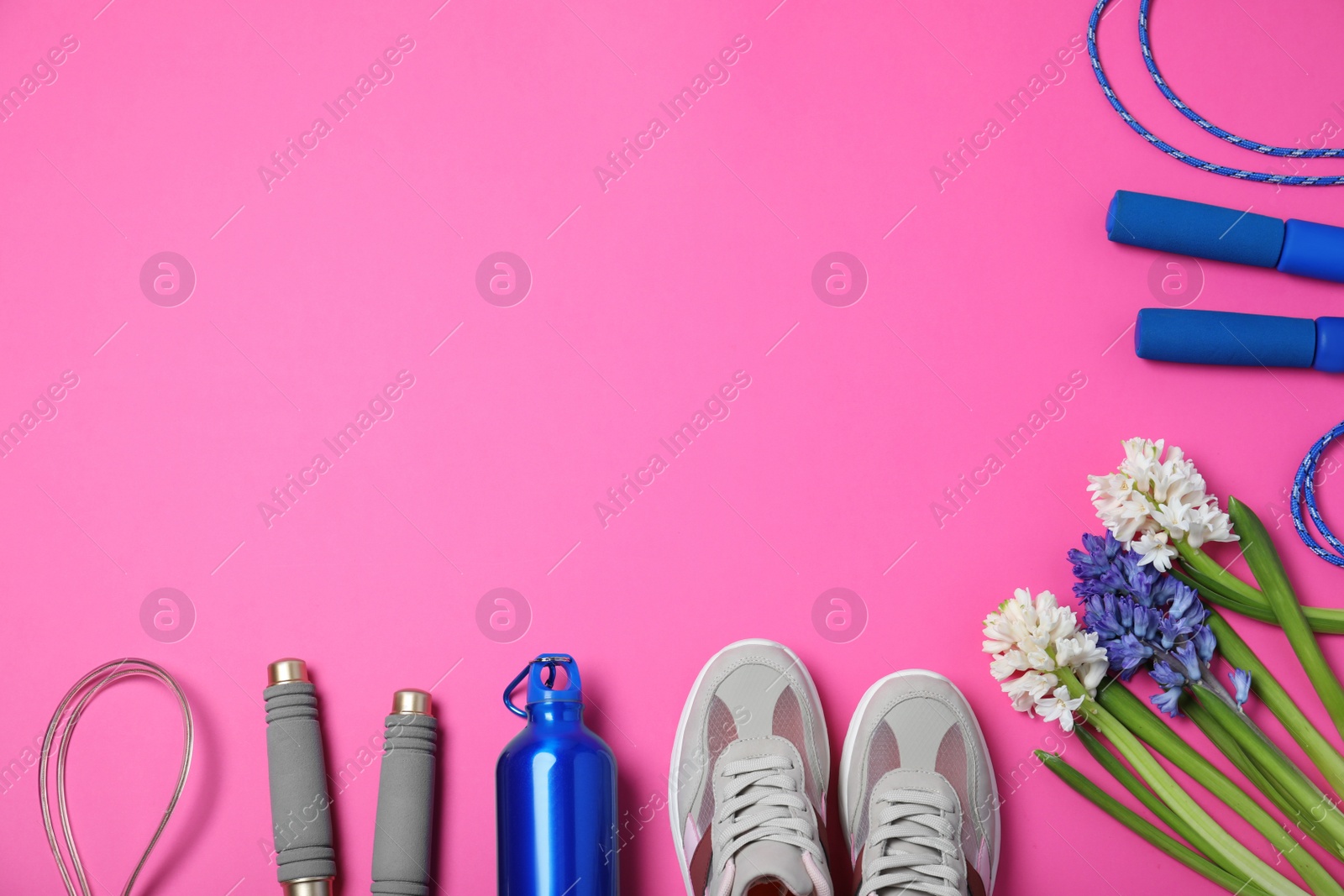 Photo of Flat lay composition with spring flowers and sports items on pink background. Space for text