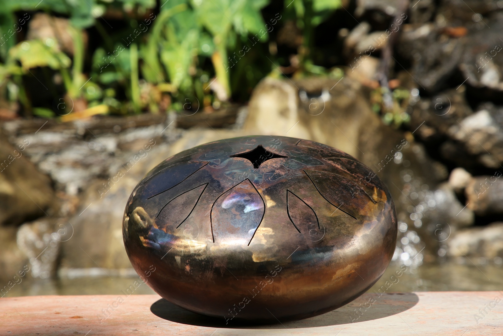 Photo of Steel tongue drum outdoors on sunny day. Percussion musical instrument