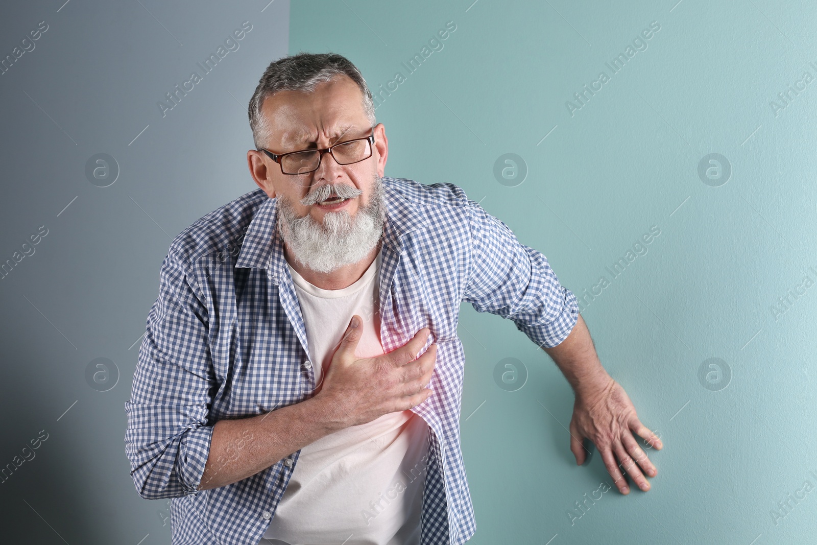 Photo of Mature man having heart attack on color background