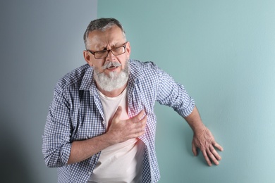 Photo of Mature man having heart attack on color background