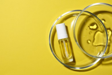 Photo of Petri dishes with bottle on yellow background, top view. Space for text