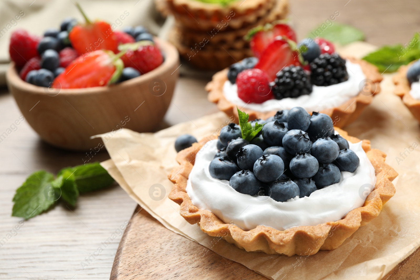 Photo of Different berry tarts on wooden table. Delicious pastries