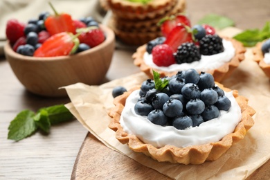 Different berry tarts on wooden table. Delicious pastries