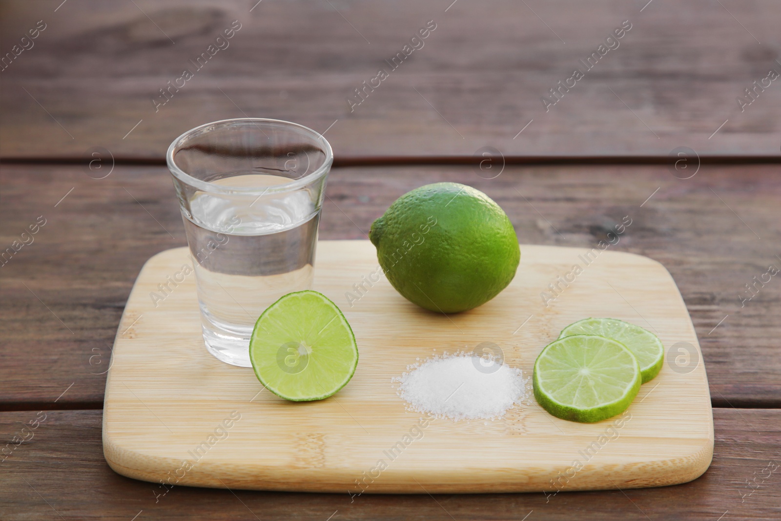 Photo of Mexican tequila shot with lime slices and salt on wooden table. Drink made from agave