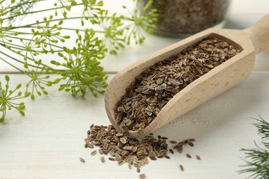 Photo of Dry seeds and fresh dill on white wooden table, closeup