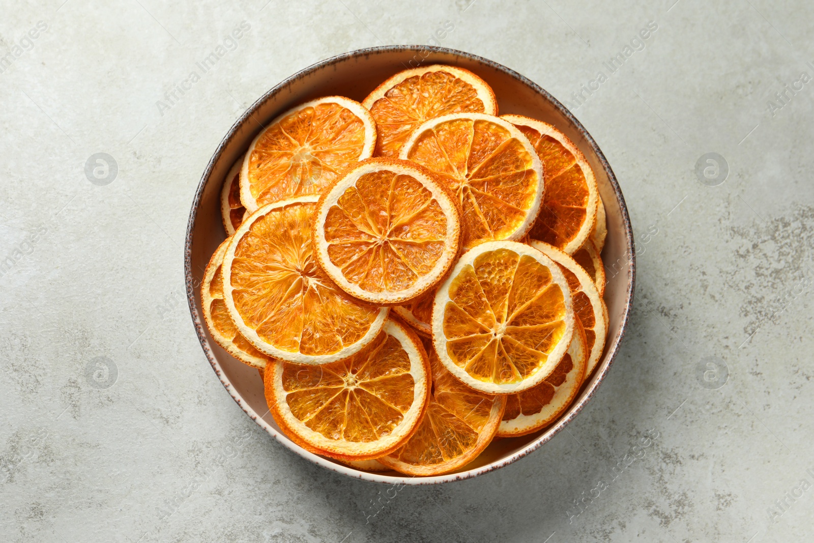 Photo of Bowl of dry orange slices on light table, top view