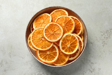 Bowl of dry orange slices on light table, top view