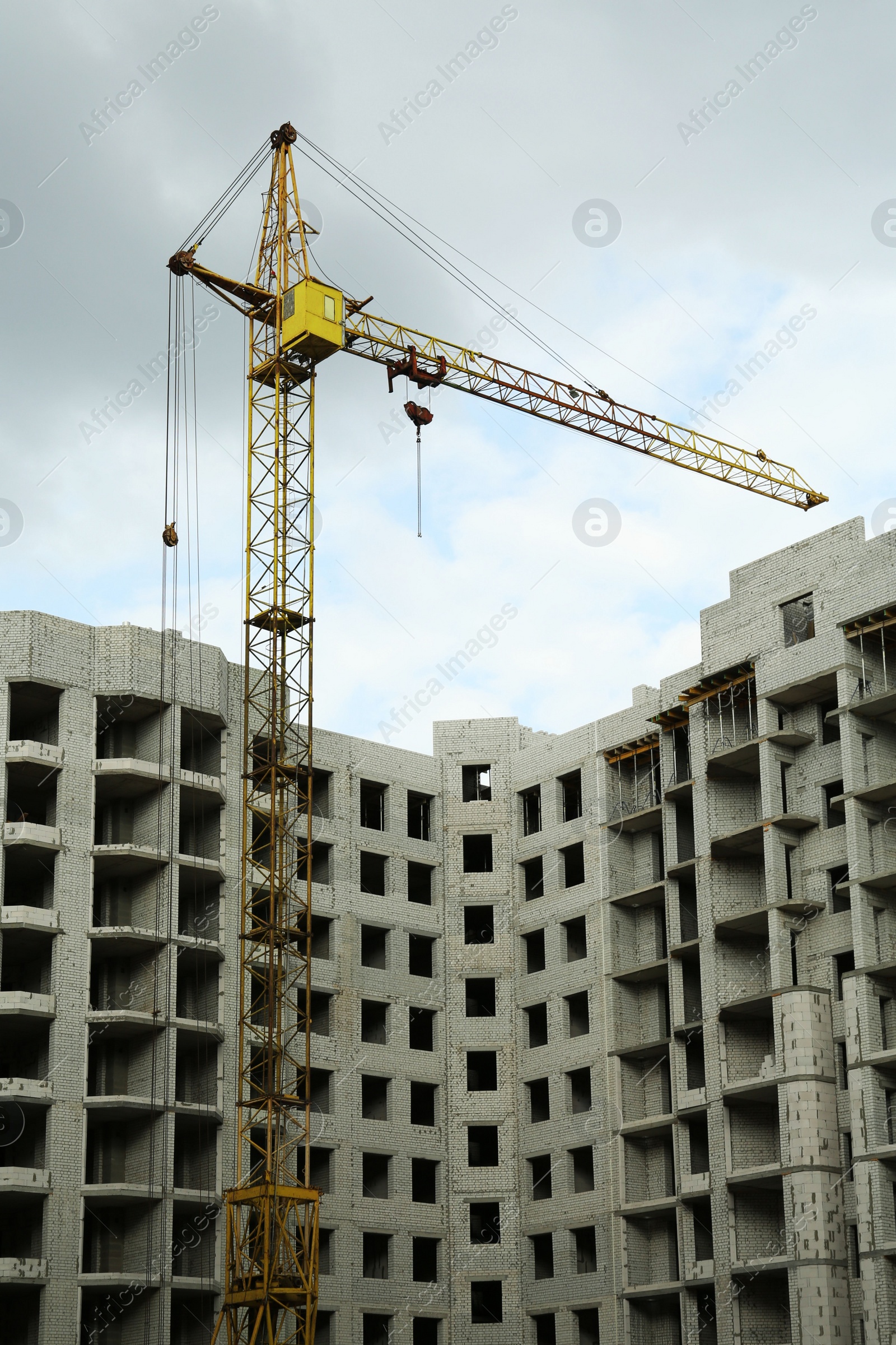 Photo of Construction site with tower crane near unfinished building, low angle view