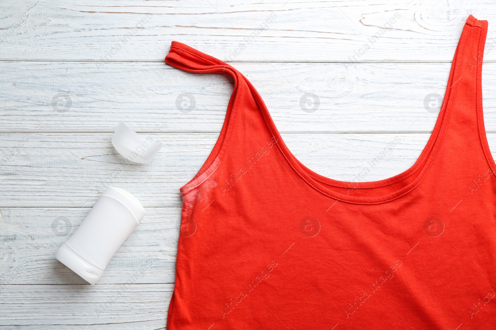 Photo of Clothes with stain and deodorant on white wooden background, top view