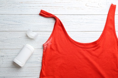 Clothes with stain and deodorant on white wooden background, top view