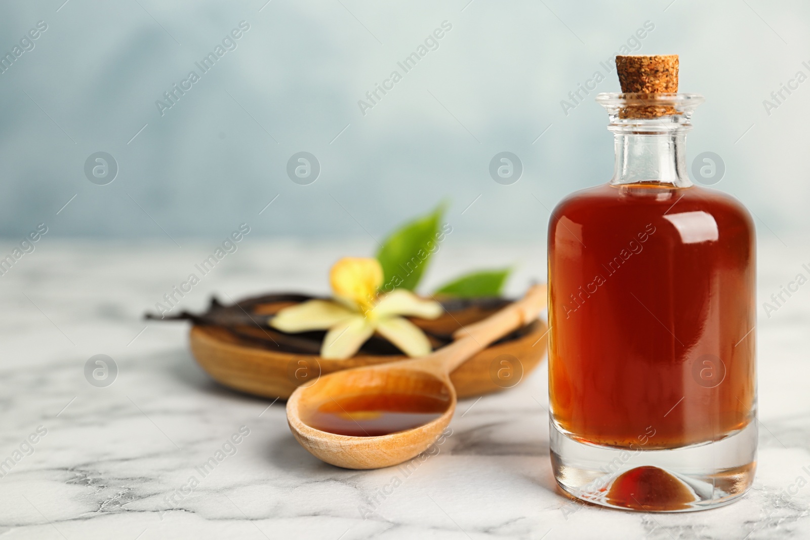Photo of Aromatic homemade vanilla extract on marble table. Space for text