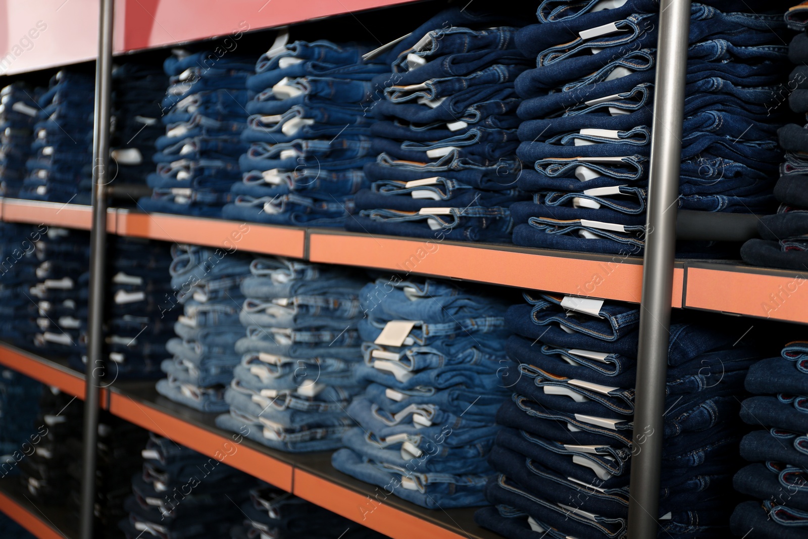 Photo of Collection of stylish jeans on shelves in shop