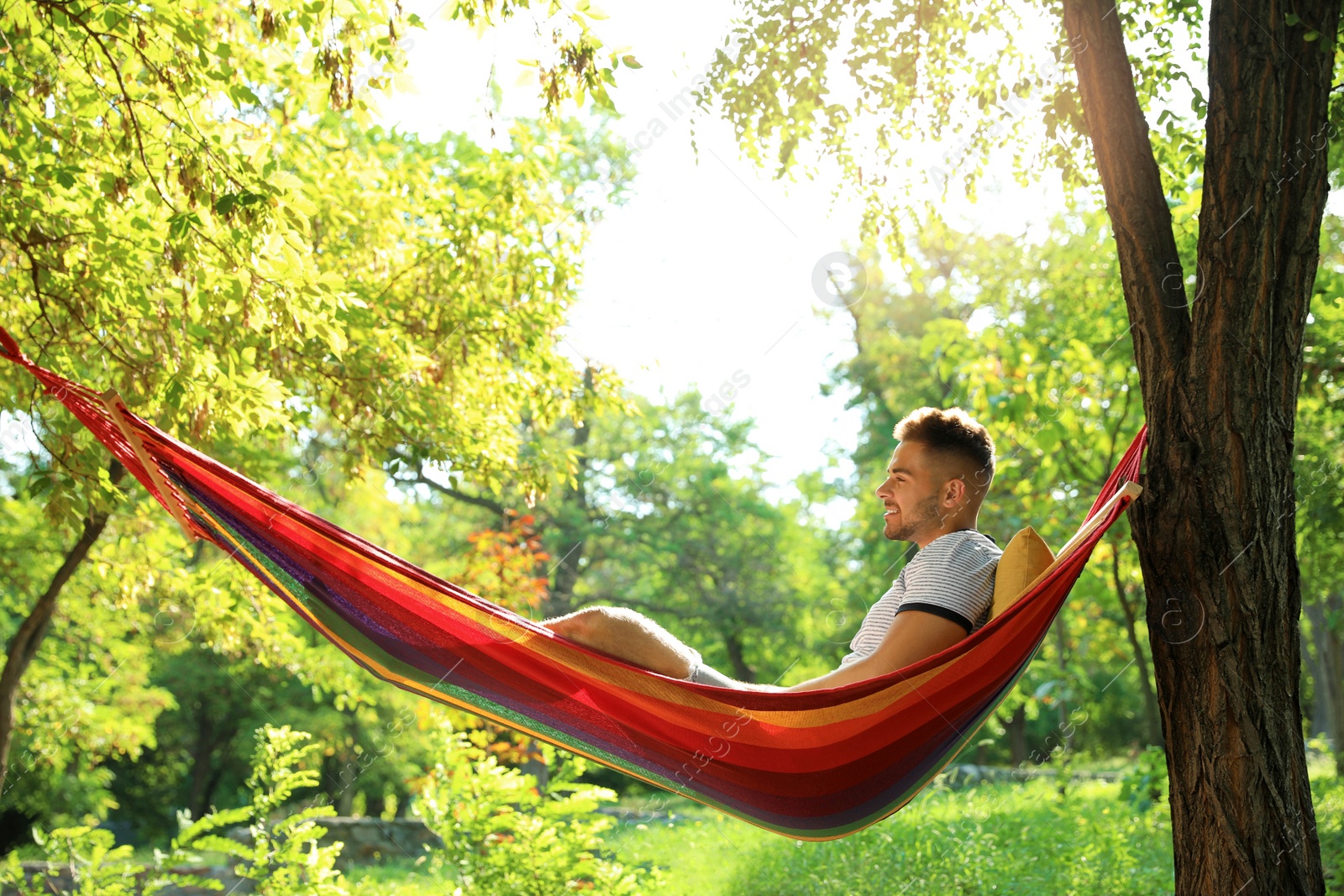 Photo of Young man resting in comfortable hammock at green garden