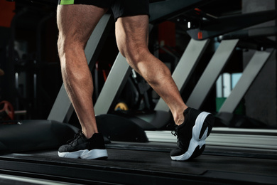 Man working out on treadmill in modern gym, closeup of legs