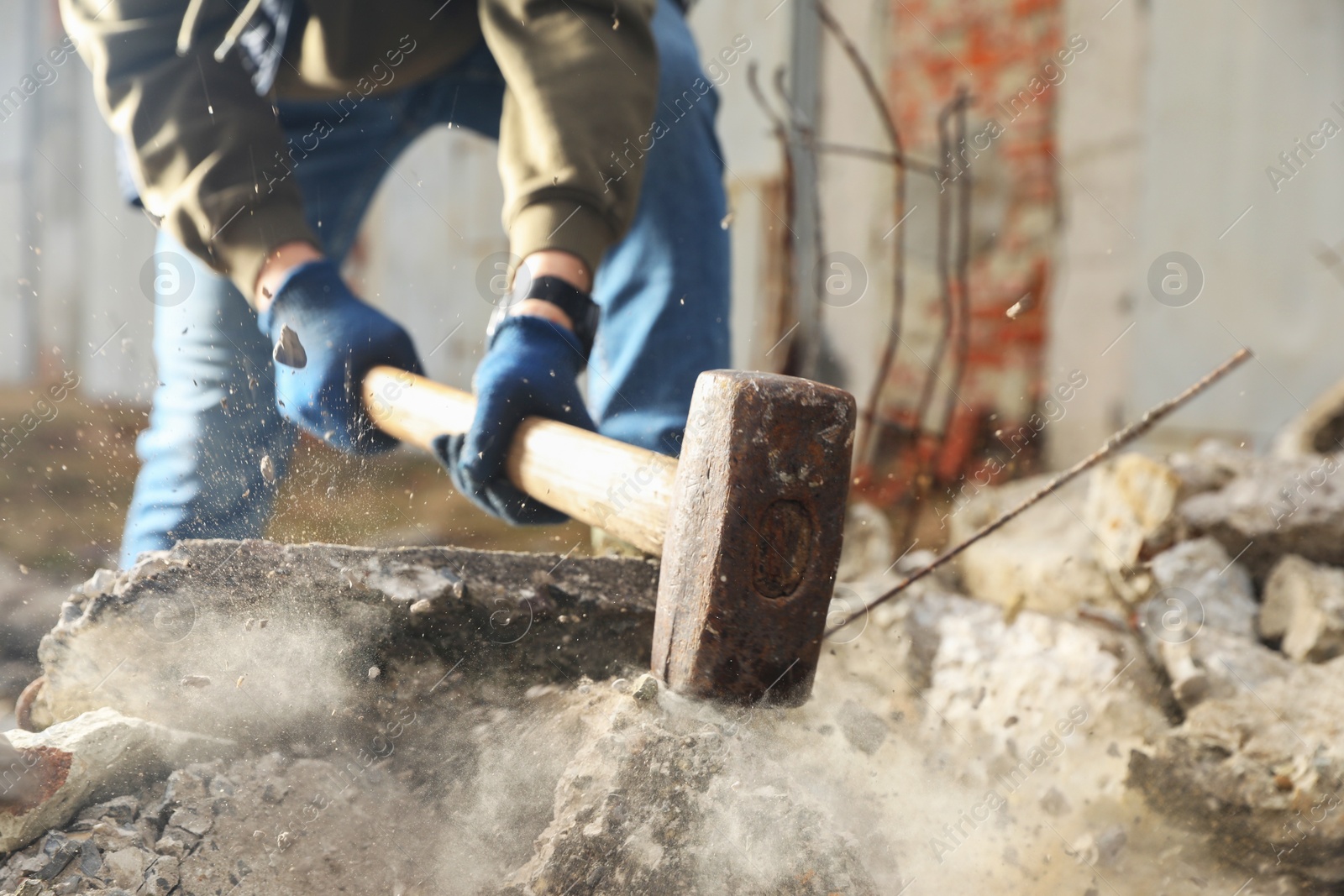 Photo of Man breaking stones with sledgehammer outdoors, closeup