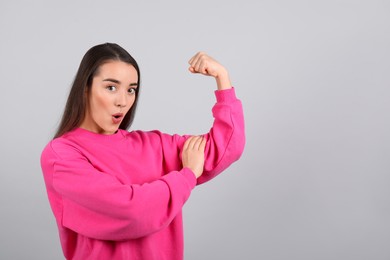 Photo of Emotional strong woman as symbol of girl power on light grey background, space for text. 8 March concept