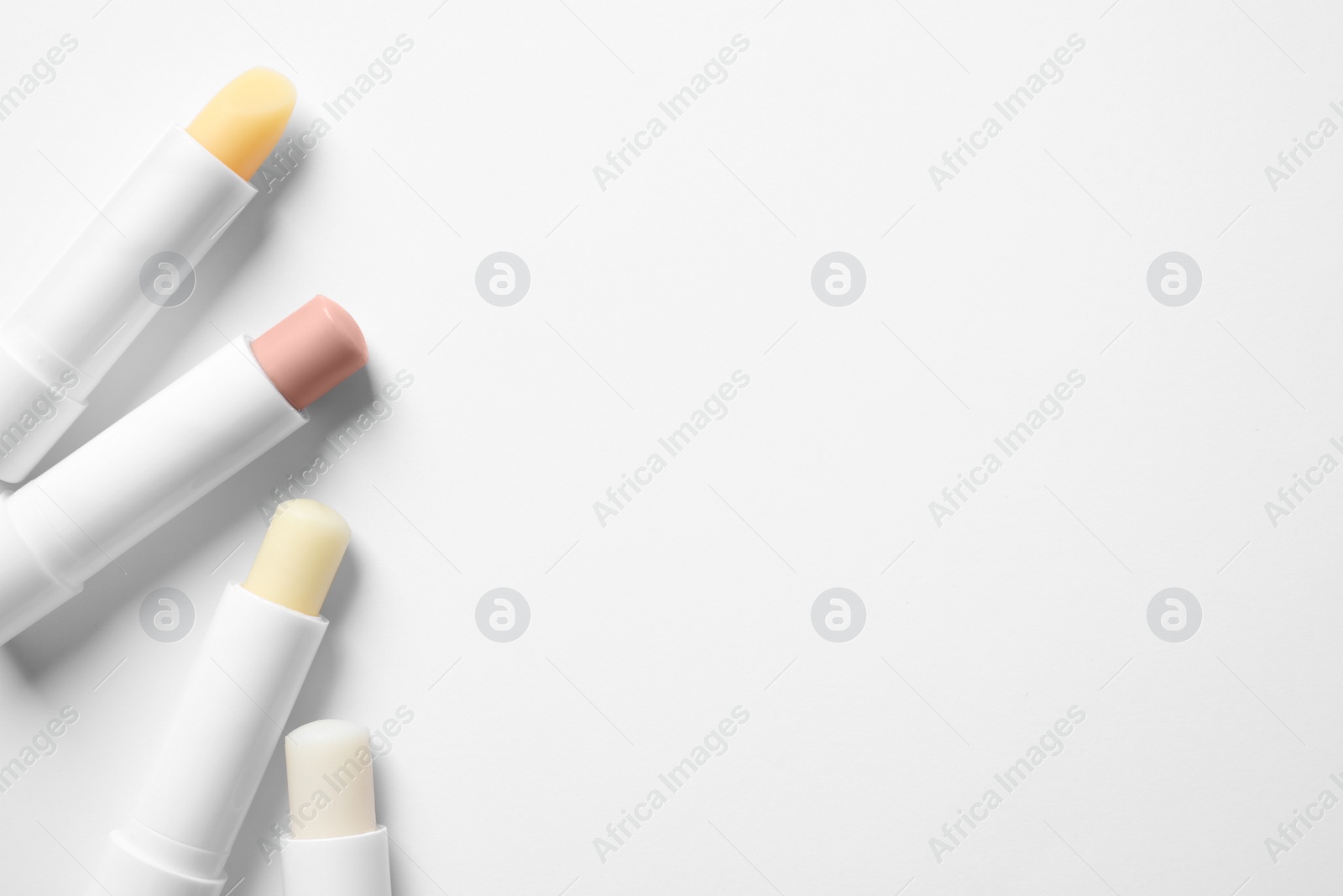 Photo of Hygienic lipsticks on white background, top view