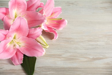 Photo of Beautiful pink lily flowers on white wooden table Space for text