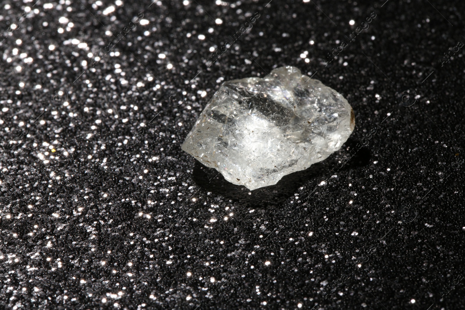 Photo of Beautiful rough diamond on dark shiny background, closeup