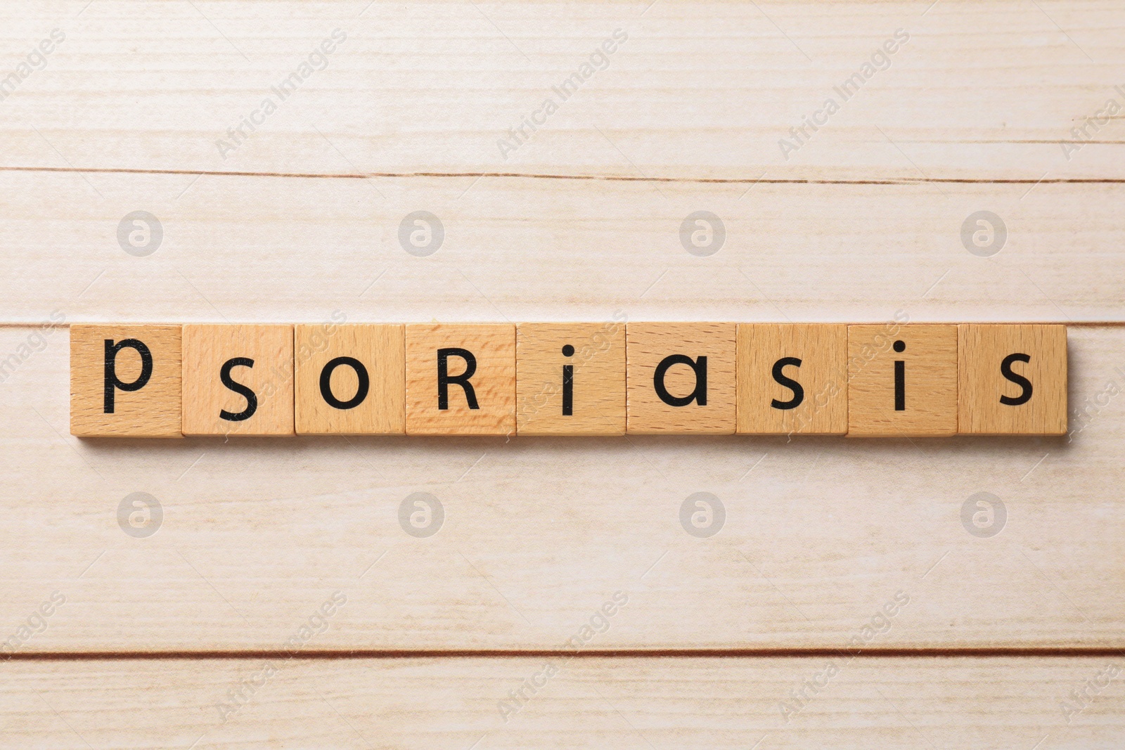 Photo of Word Psoriasis made of squares with letters on white wooden table, top view