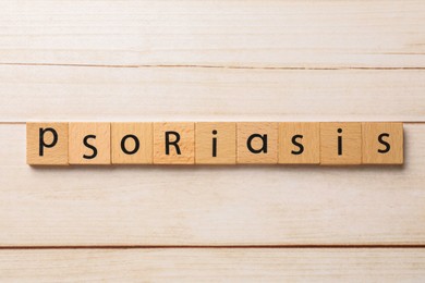 Word Psoriasis made of squares with letters on white wooden table, top view