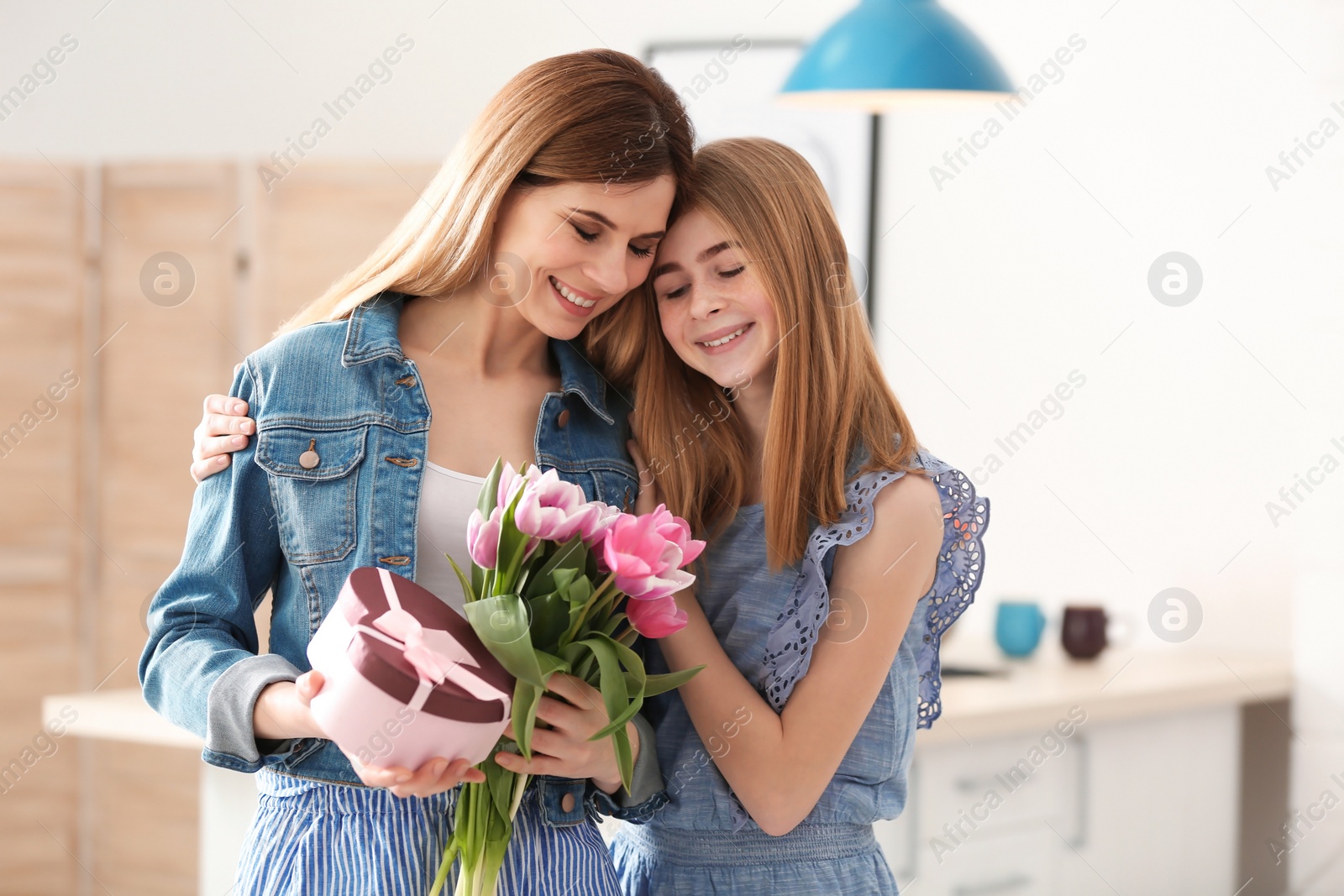 Photo of Teenage daughter congratulating happy woman on Mother's Day at home