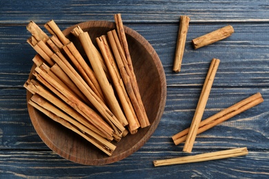 Aromatic cinnamon sticks on blue wooden table, flat lay