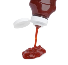 Photo of Pouring tasty red ketchup from bottle isolated on white
