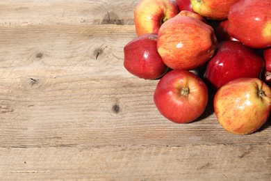 Photo of Many fresh apples with water drops on wooden table, top view. Space for text