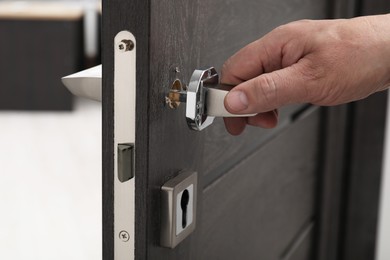 Photo of Handyman repairing door handle indoors, closeup view