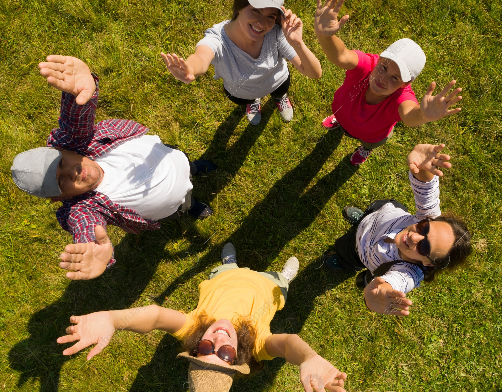 Image of Top aerial view of happy people standing in circle on green grass. Drone photography