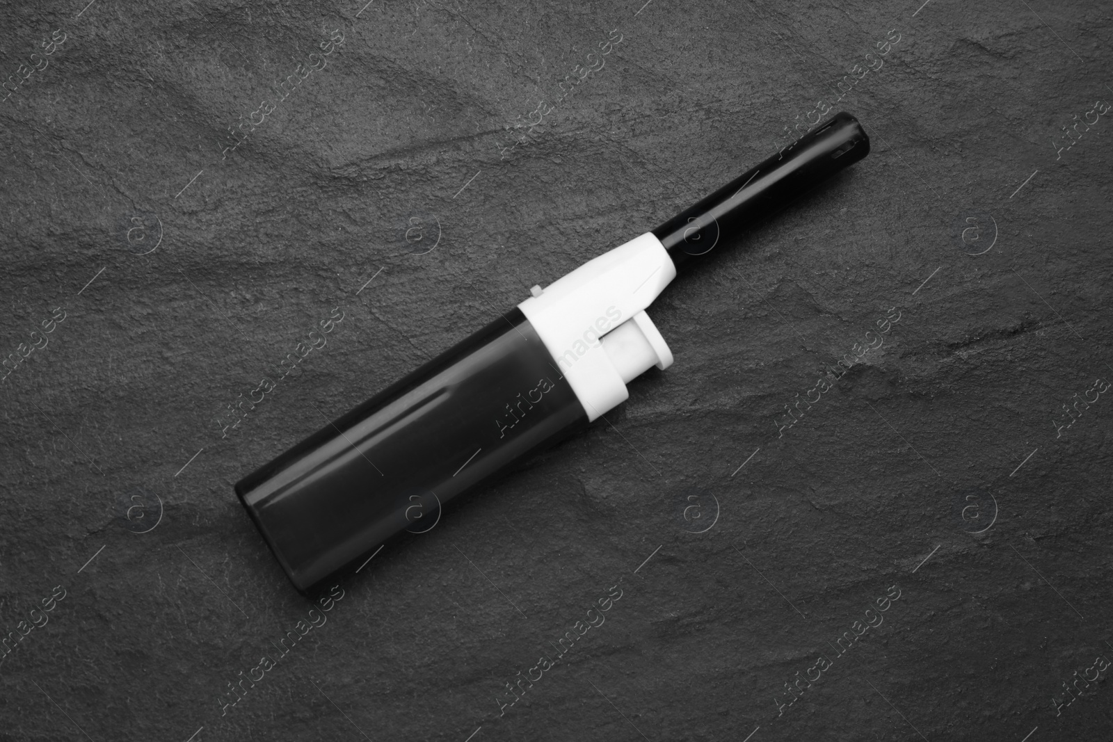 Photo of One gas lighter on black textured background, top view