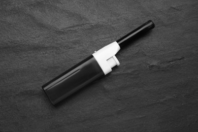 Photo of One gas lighter on black textured background, top view