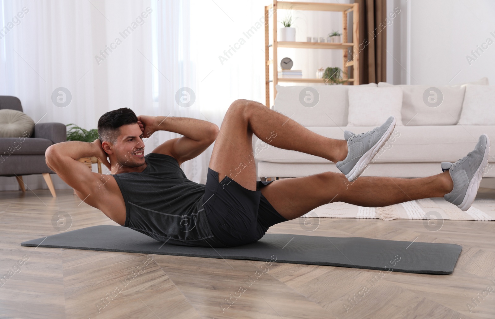 Photo of Handsome man doing abs exercise on yoga mat at home