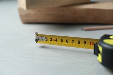 Tape measure on light grey table, closeup. Construction tool