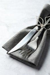 Stylish cutlery and napkin on white marble table