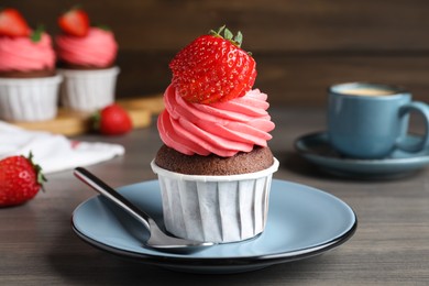 Sweet cupcake with fresh strawberry on wooden table