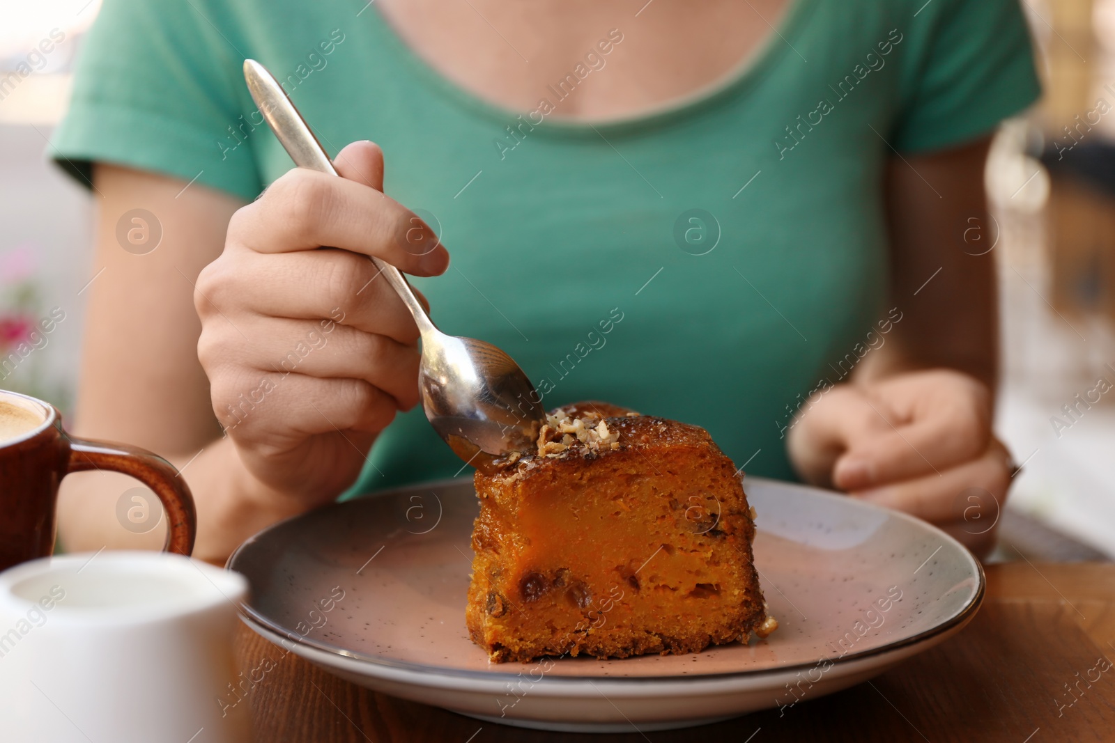 Photo of Woman eating slice of carrot cake at table, closeup